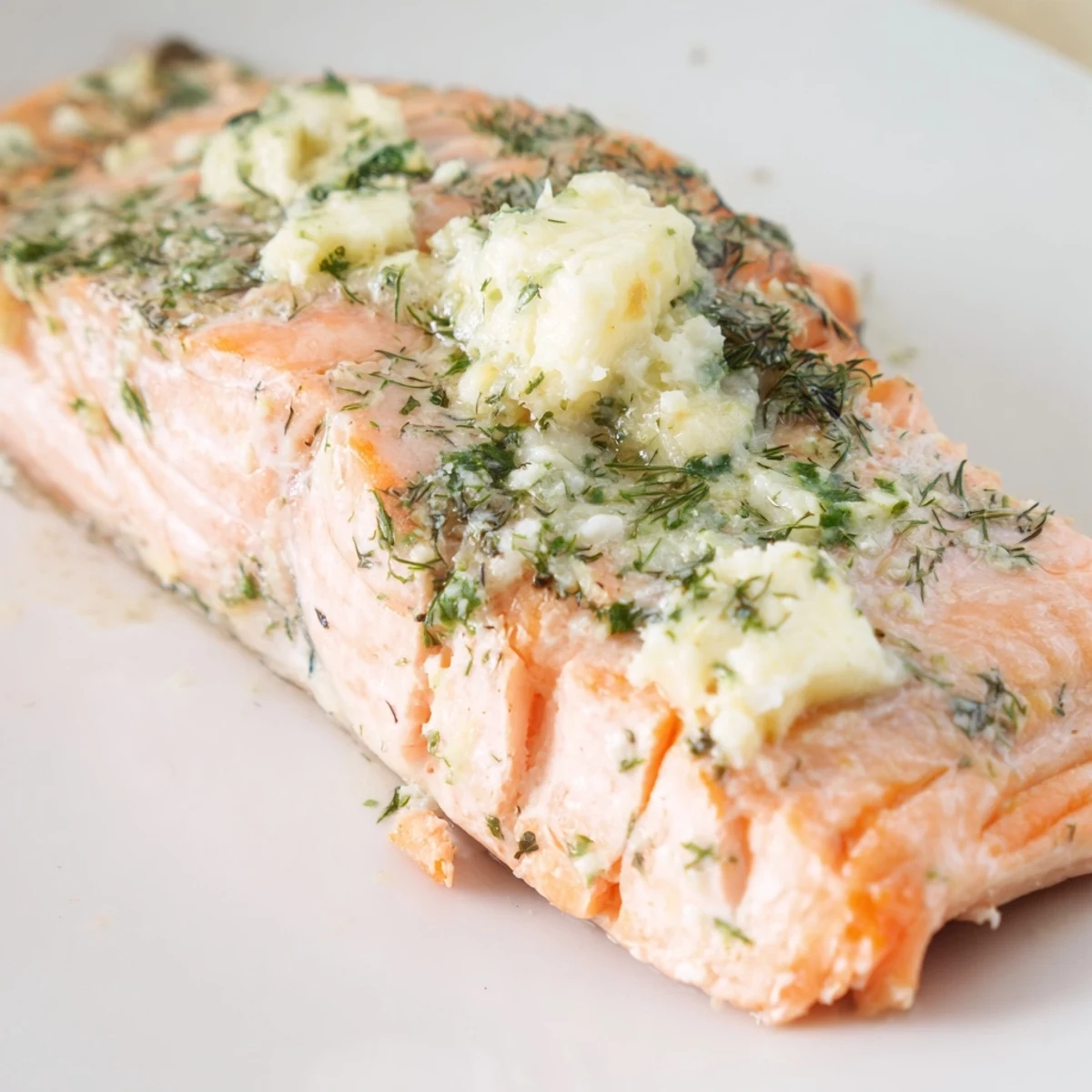 Golden-brown Baked Salmon with Lemon Herb Butter flaking easily on a parchment-lined baking sheet, garnished with fresh herbs.