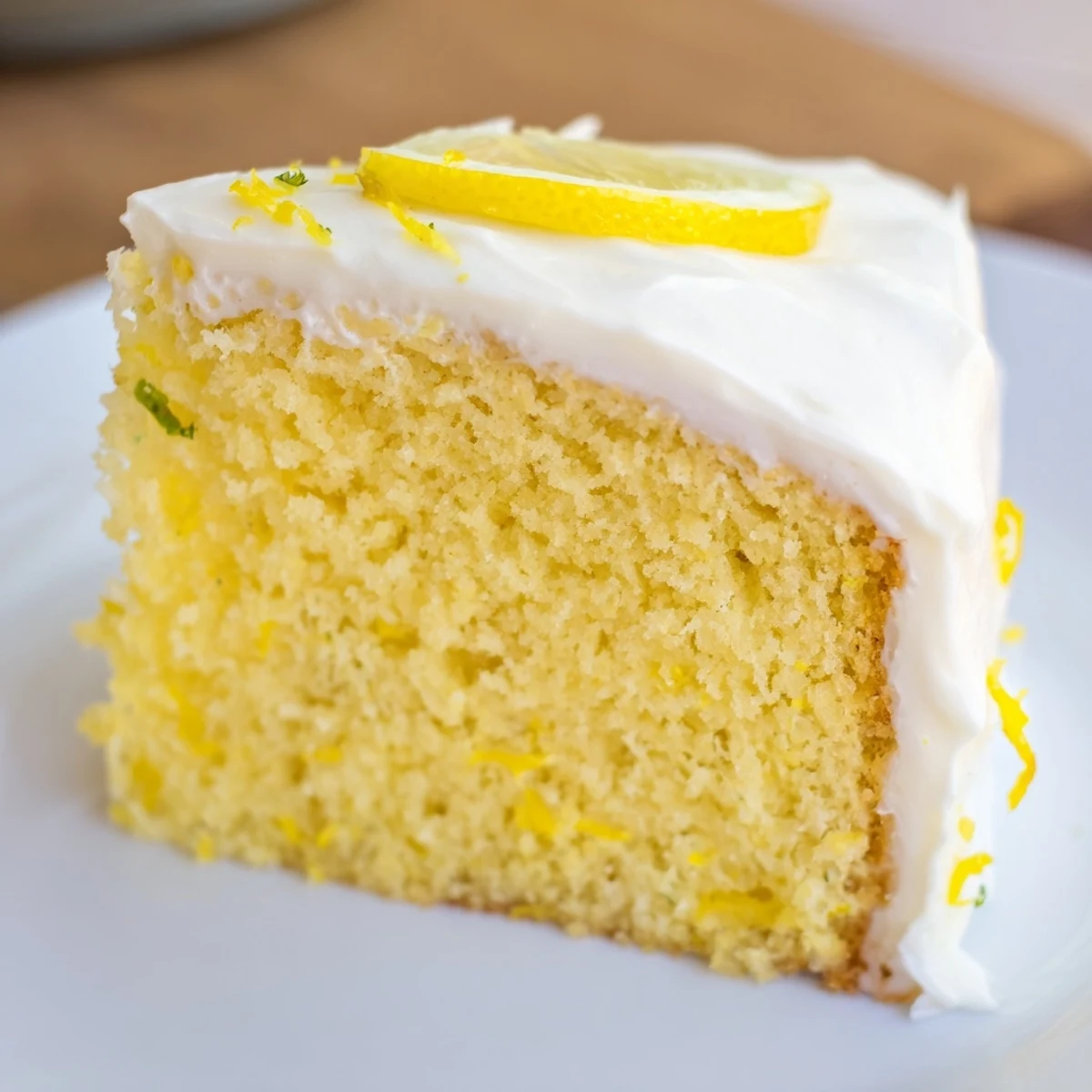 A freshly baked Lemon Cake Slice with Frosting sits beside a glass of milk for a classic American dessert pairing.