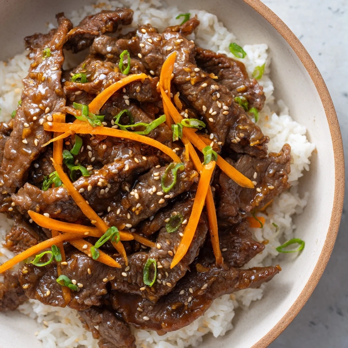 Tender beef and crisp vegetables over jasmine steamed rice in a bowl, ready to be enjoyed with chopsticks.
