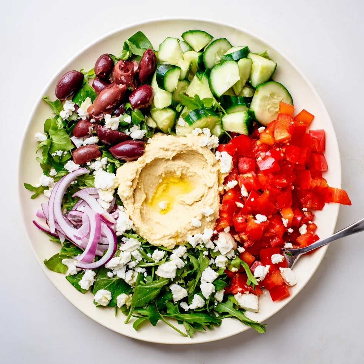 A vibrant Mediterranean Salad with Hummus showcases crisp cucumbers, juicy tomatoes, and creamy chickpea dip, perfect for a fresh light lunch.