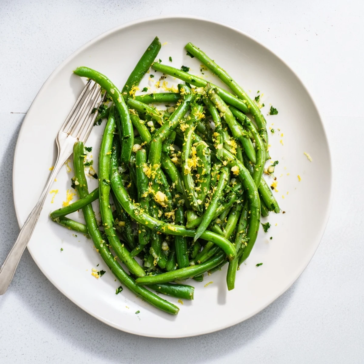 Bright green beans tossed with minced garlic and fresh lemon zest in a skillet, finished with parsley for a vibrant side dish.