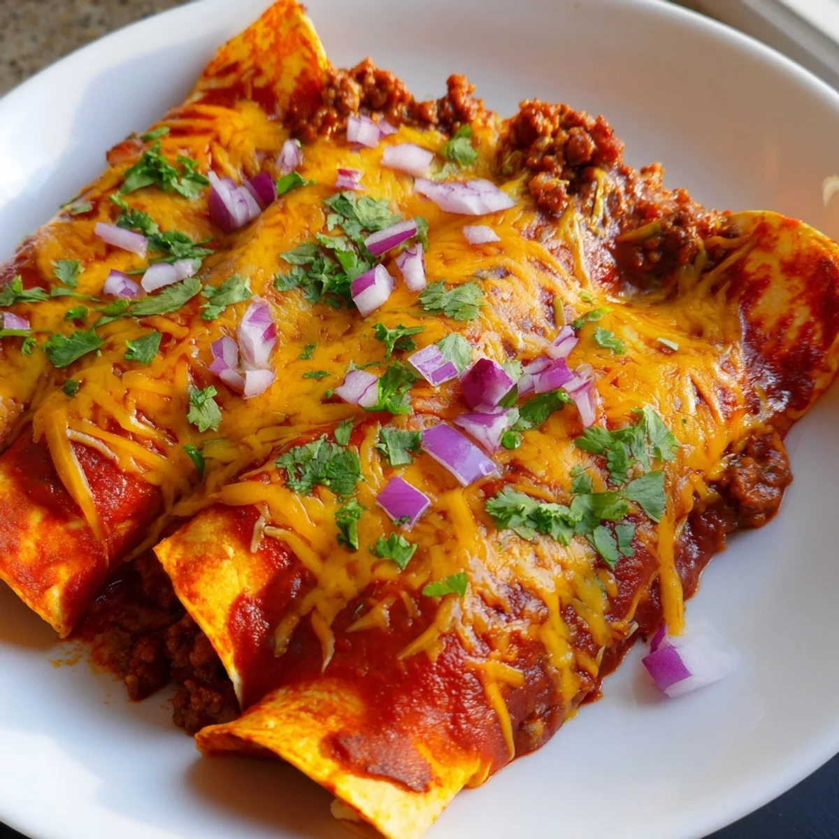 Golden-brown Championship Beef Enchiladas with Red Sauce drizzled with spicy sauce and fresh cilantro.
