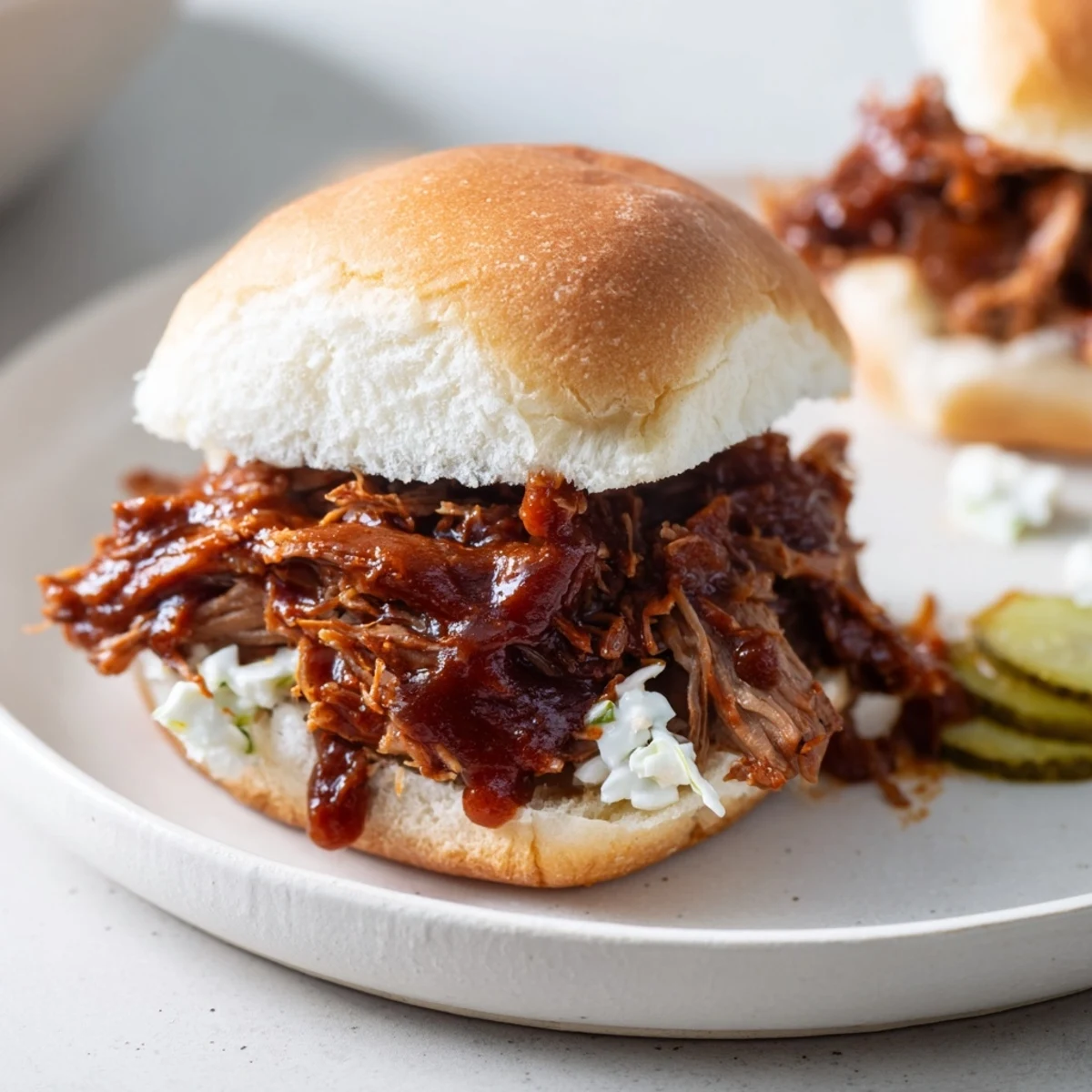 Shredded beef brisket sliders with homemade BBQ sauce, served on toasted buns with crisp coleslaw and pickles for added crunch.