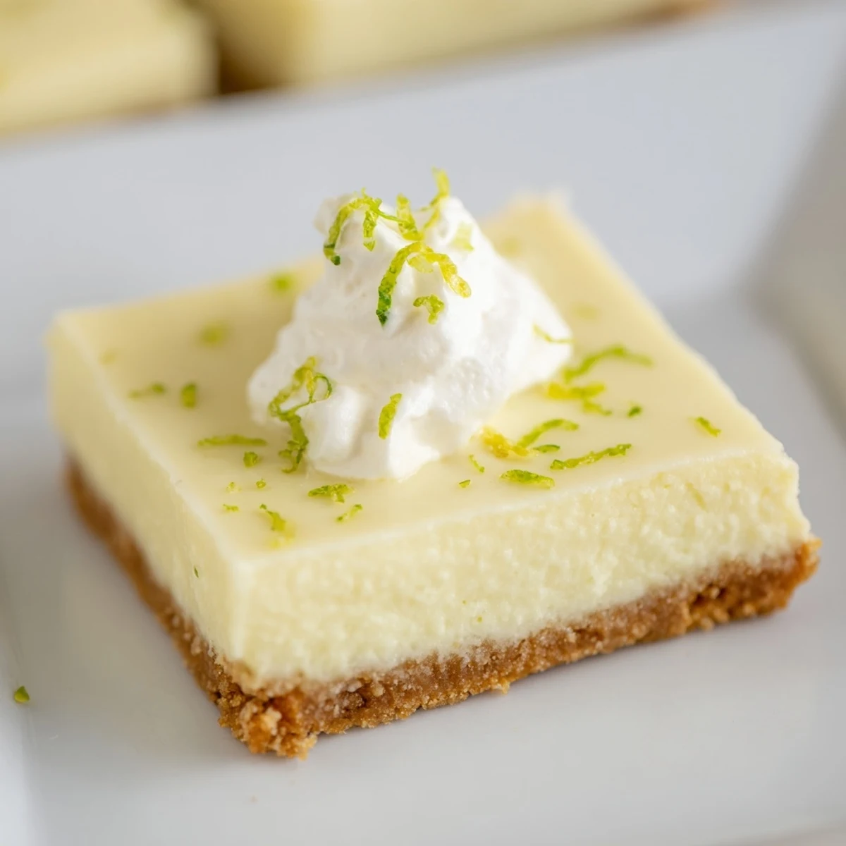 Freshly baked Key Lime Pie Bars with a golden graham cracker crust and vibrant green filling, topped with lime zest.  