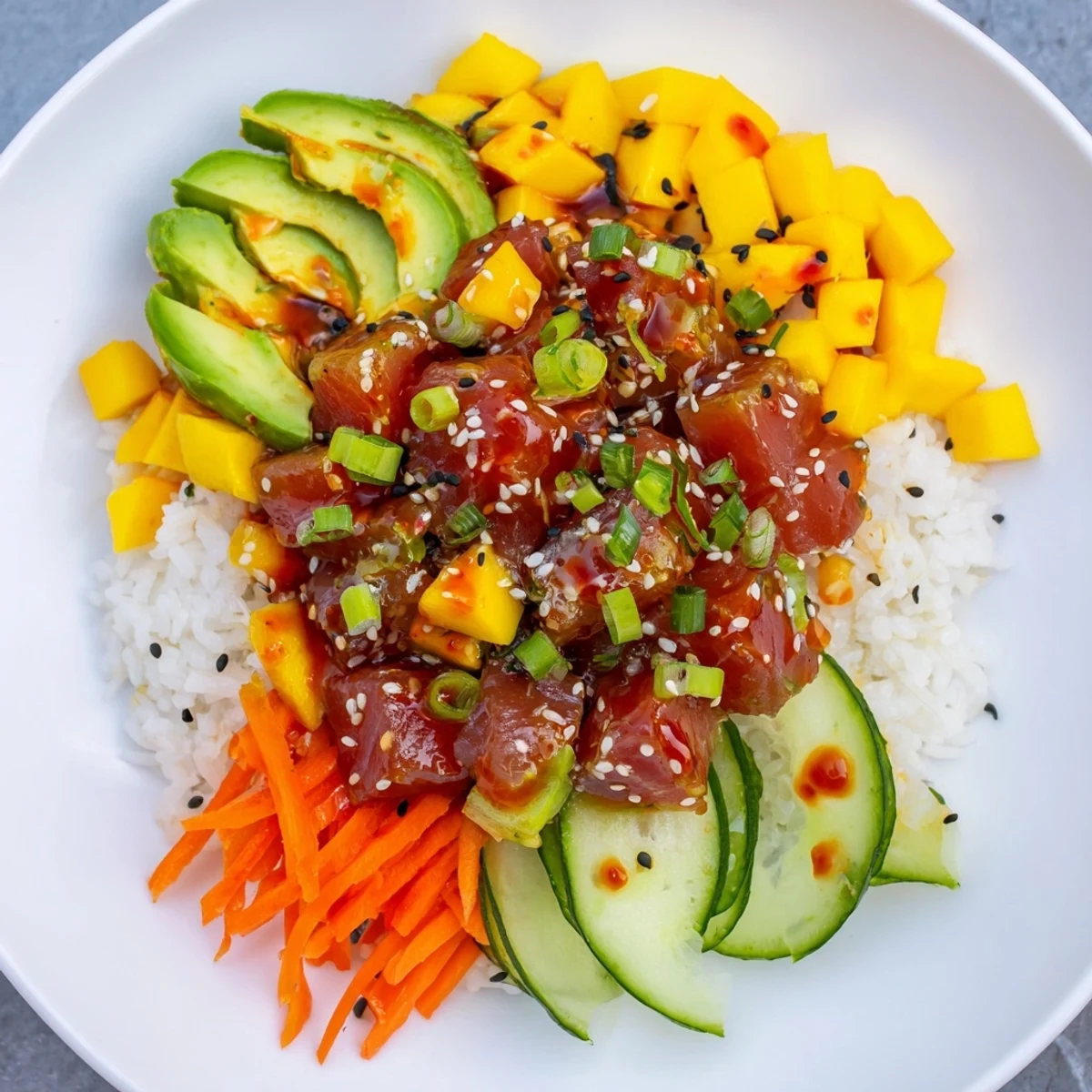 Bright and spicy tuna poke bowl with sweet mango and creamy avocado, garnished with sesame seeds and fresh herbs.