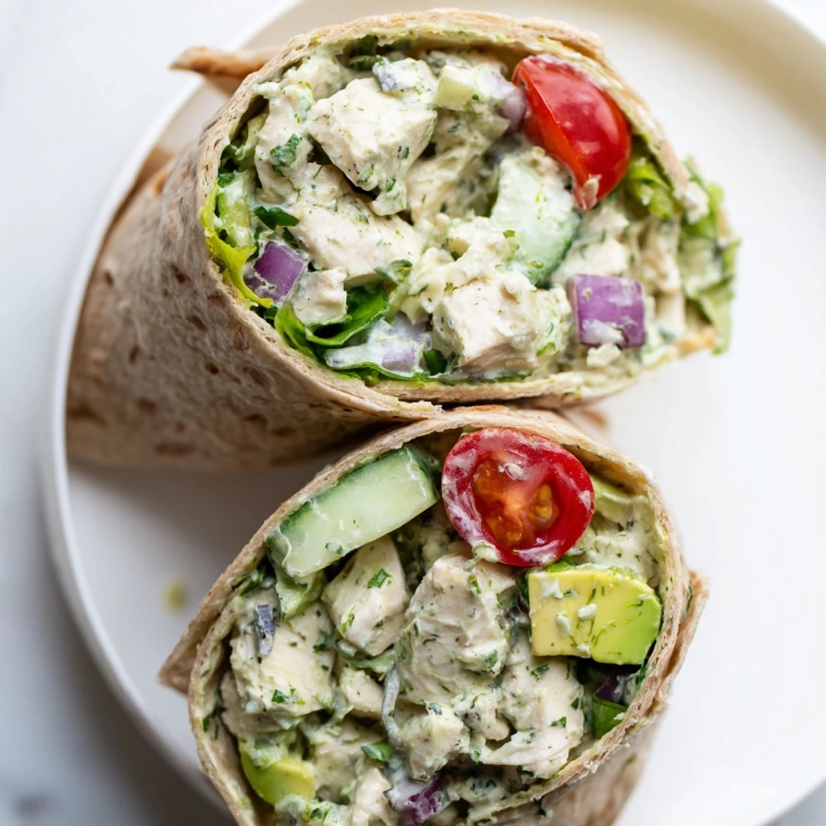 Green Goddess Chicken Salad Wraps filled with shredded chicken, crisp celery, cucumbers, and vibrant greens in a whole wheat tortilla. 