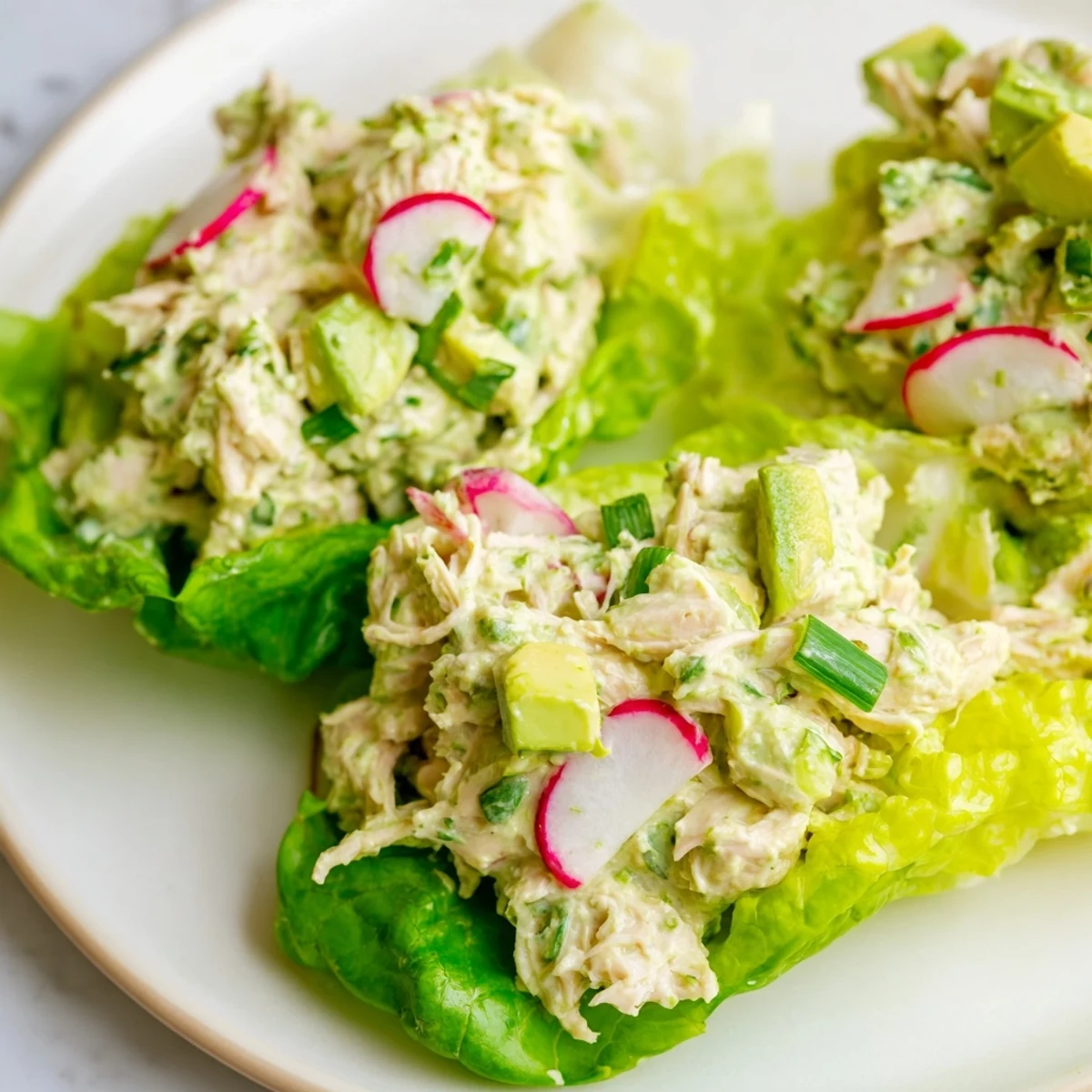 Crisp butter lettuce cups cradling creamy Green Goddess Chicken Salad Lettuce Wraps garnished with fresh herbs and sliced radishes.
