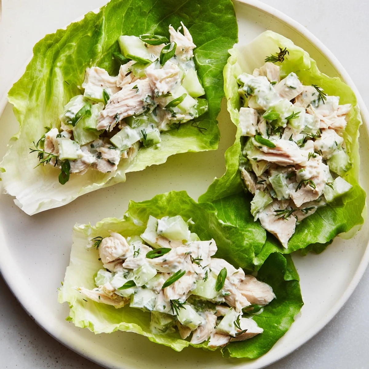 Hearty Green Goddess Chicken Salad Lettuce Wraps feature diced chicken, celery, cucumber, and avocado in herby dressing.