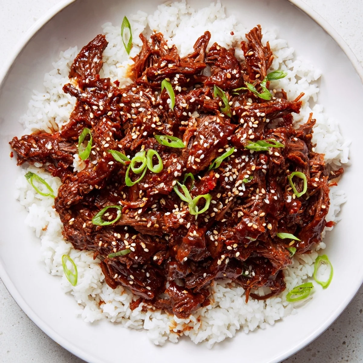 Savory Slow Cooker Korean Beef shredded and piled onto crisp lettuce wraps, topped with green onions and toasted sesame seeds.