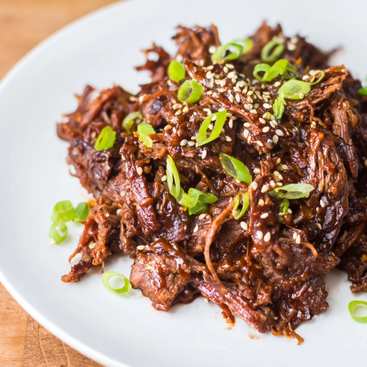 Close-up of tender, shredded Crock Pot Korean Beef glistening in a thick, savory-sweet sauce over fluffy rice.