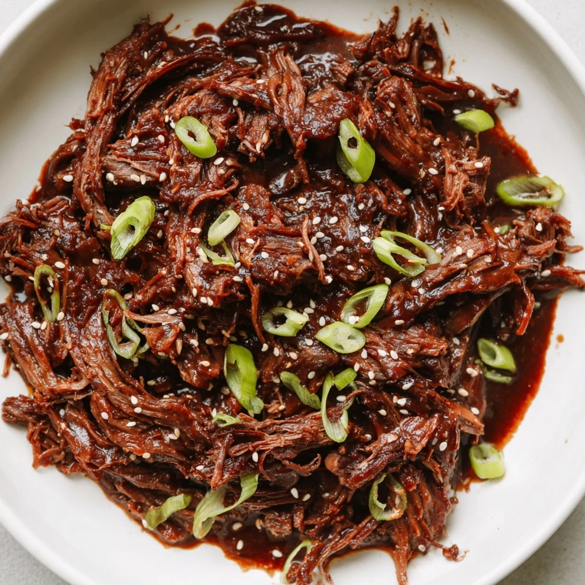 A slow cooker pot filled with aromatic Crock Pot Korean Beef topped with fresh green onions and sesame seeds.
