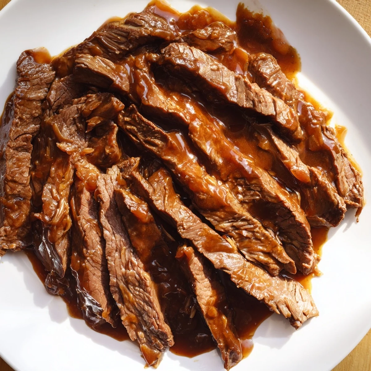 A close-up of glossy, saucy Ultimate Slow Cooker Mongolian Beef with vibrant sliced green onions on top.