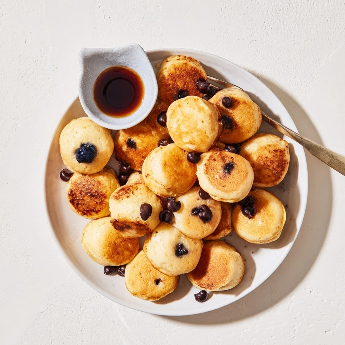 Overhead shot of moist Pancake Poppers arranged on a white plate, ready to be dipped in fruit preserves or honey.