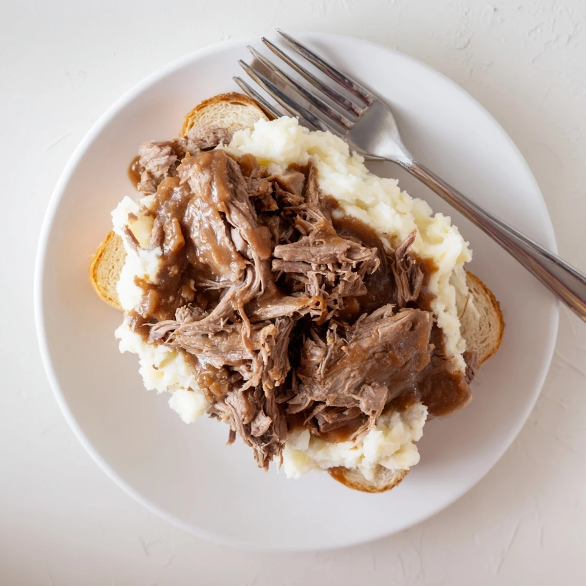 Warm Slow Cooker Beef Manhattan served with tender beef, smooth mashed potatoes, and savory gravy over thick white bread.