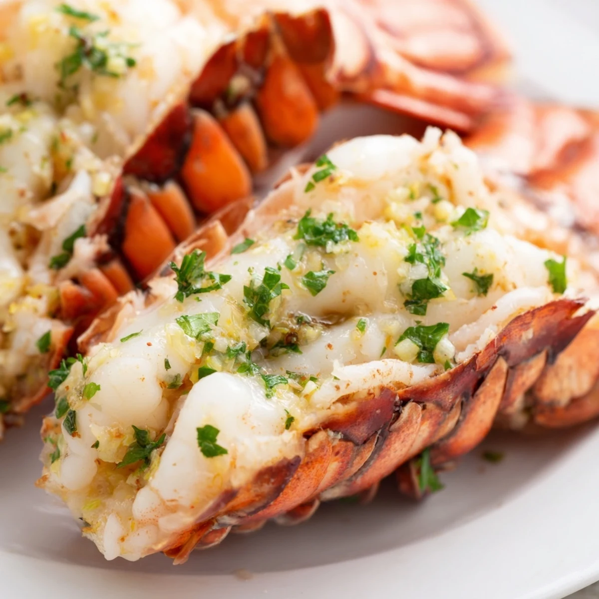 A close-up of Smoked Lobster Tails With Garlic Butter on a rustic board with garnishes.