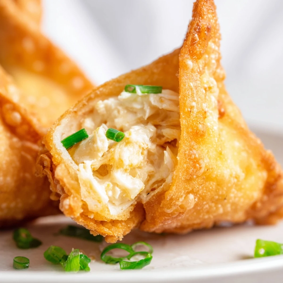 A close-up photo of Crispy Crab Rangoon Bombs with Creamy Filling shows the rich, creamy crab and cheese filling peeking out.