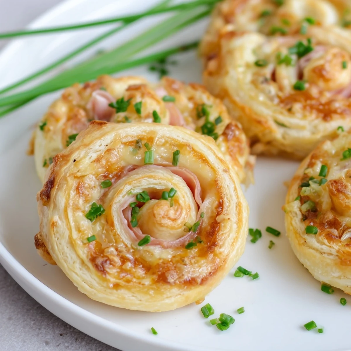 Golden-baked Ham and Cheese Pinwheels show flaky puff pastry spirals with melted Swiss cheese and savory ham slices.