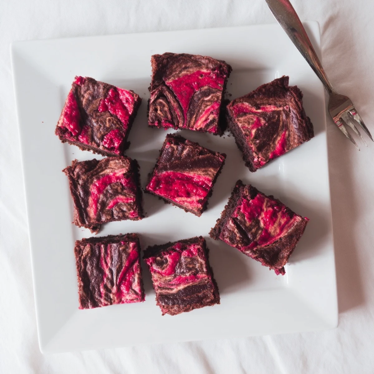 Fudgy Raspberry Swirl Brownies cooling on a wire rack with visible marbled pink ribbons through rich dark chocolate.