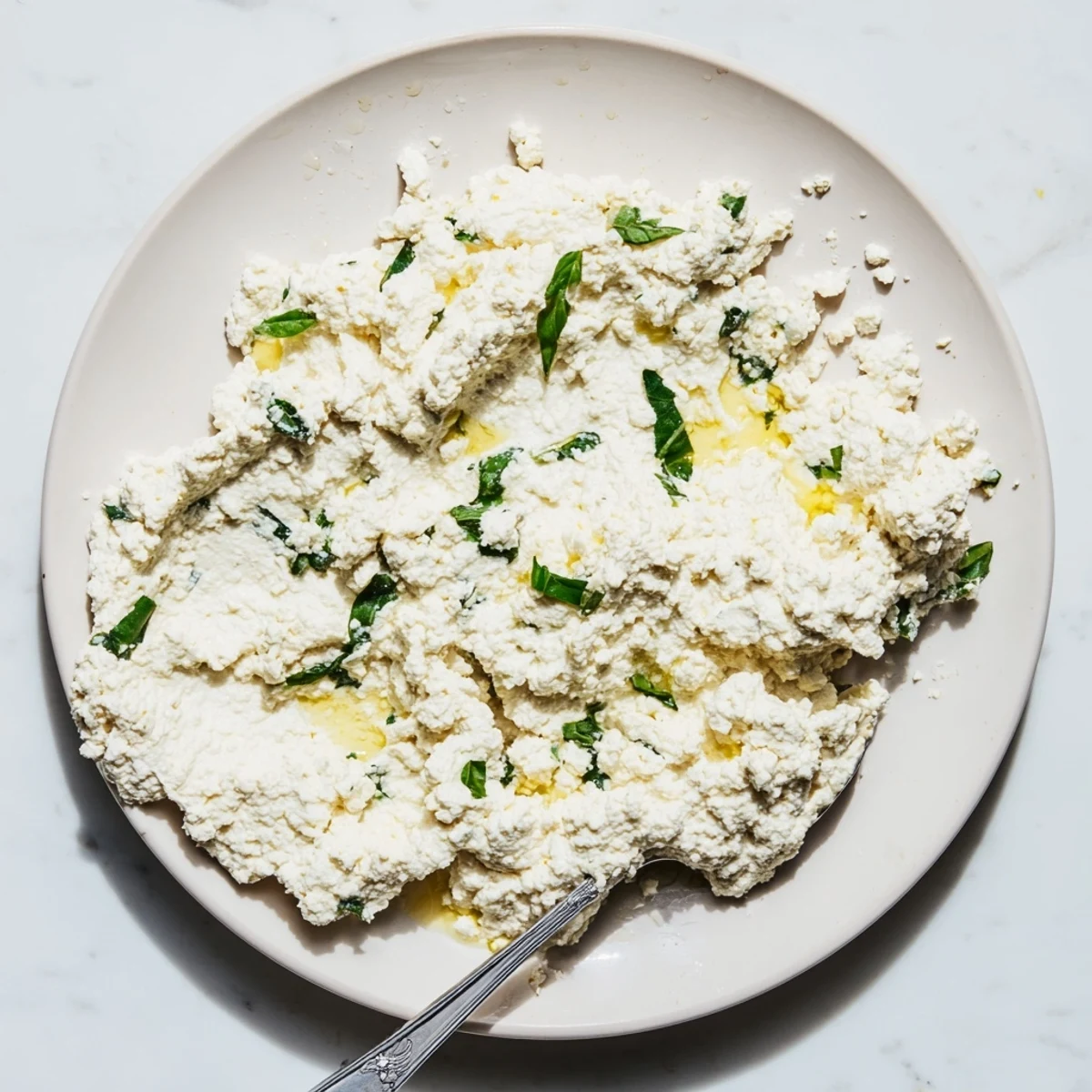 A bowl of Tofu Ricotta with a lemon wedge and fresh herbs, ready to be added to a baked lasagna.