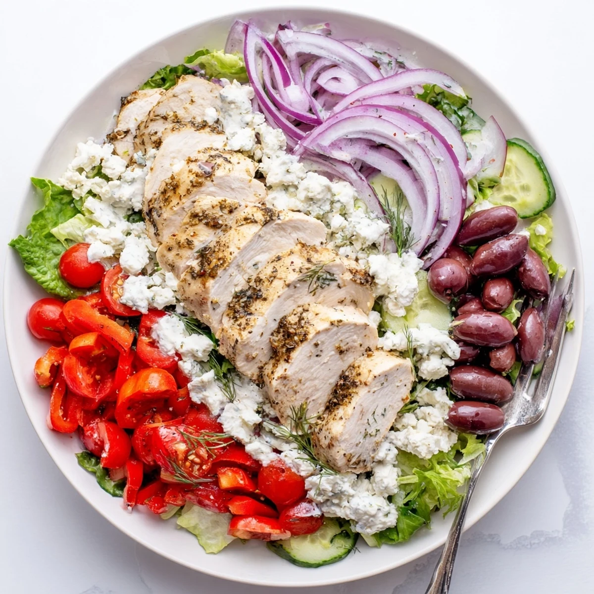 Fresh Tzatziki Chicken Salad served on a plate with red onion, feta cheese, and dill garnish.