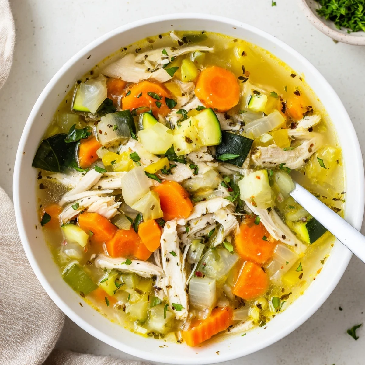 Cozy mug of The Best Healing Chicken Soup garnished with bright lemon and leafy greens, ready to enjoy.