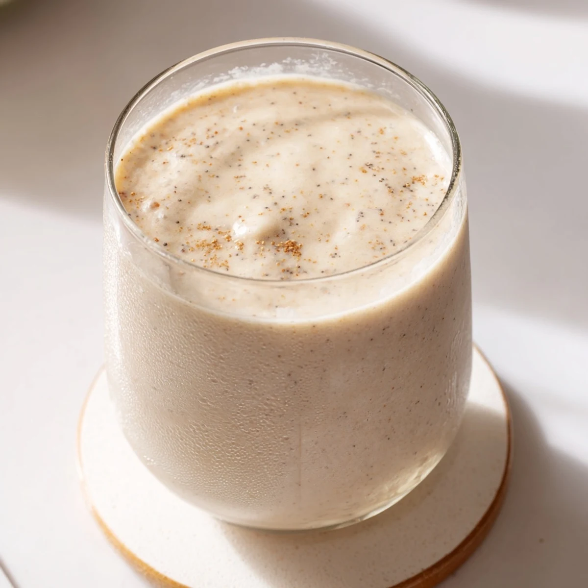 Creamy Greek yogurt banana smoothie poured into a tall glass with banana slices on top