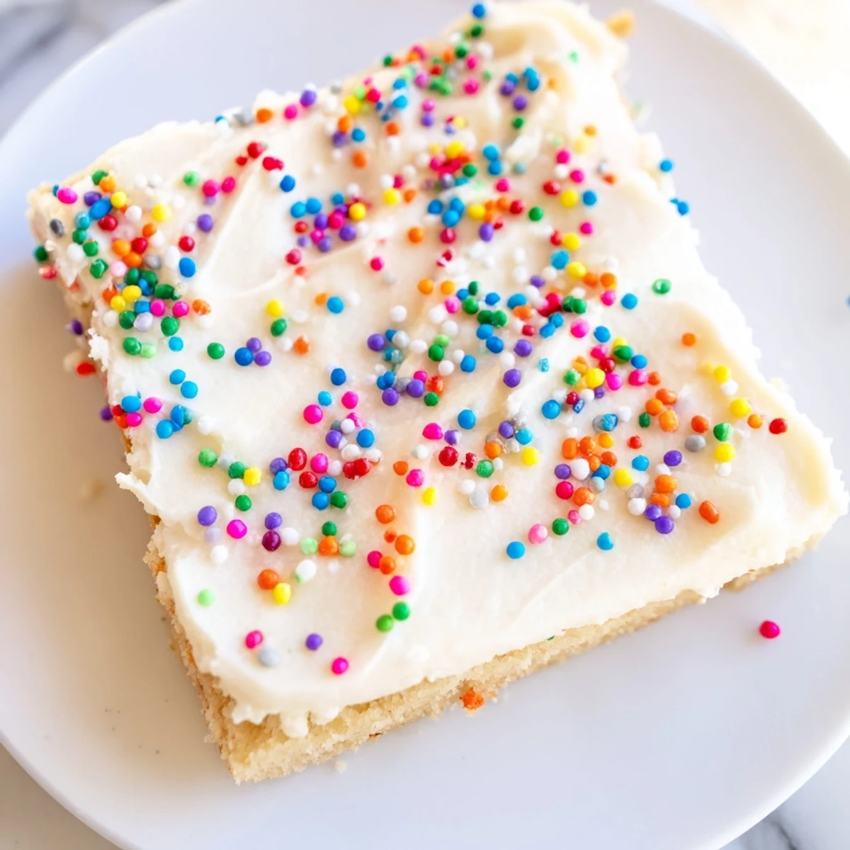 Buttery sugar cookie bars spread with smooth vanilla frosting on a rectangular serving platter