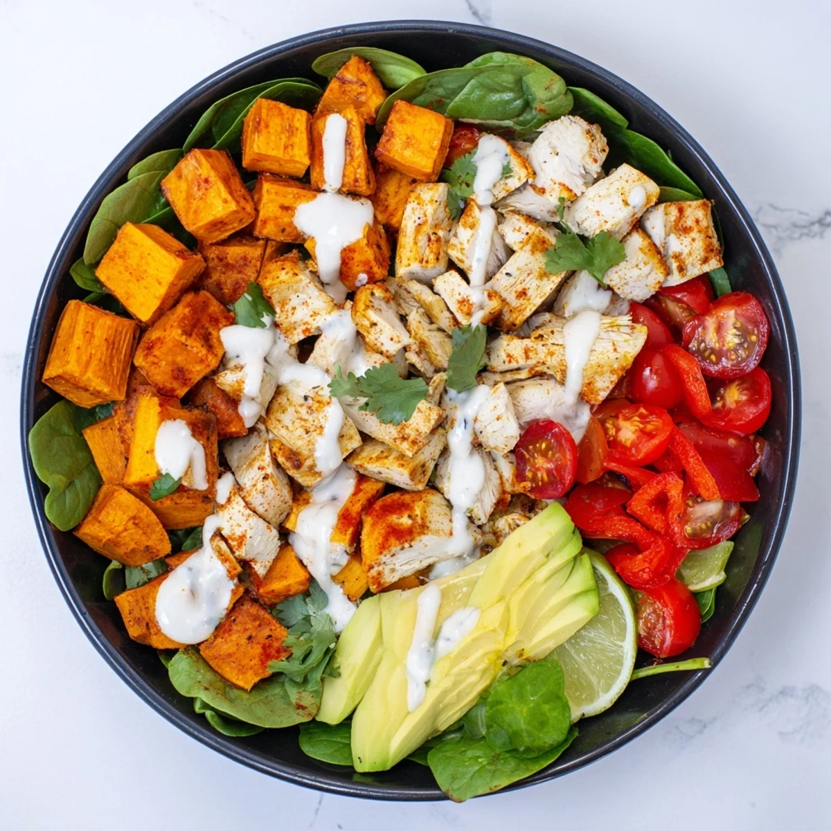 Healthy chicken sweet potato bowl topped with sliced chicken breast, caramelized sweet potatoes, cherry tomatoes, and fresh cilantro garnish