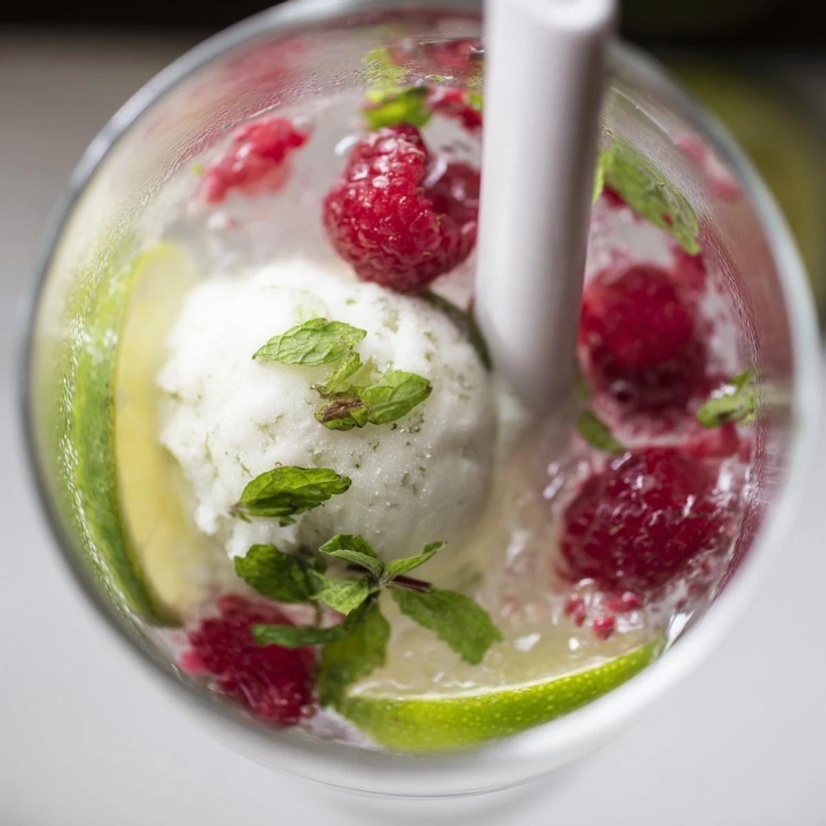 Refreshing non-alcoholic mojito float featuring muddled fresh raspberries mint and lime garnish