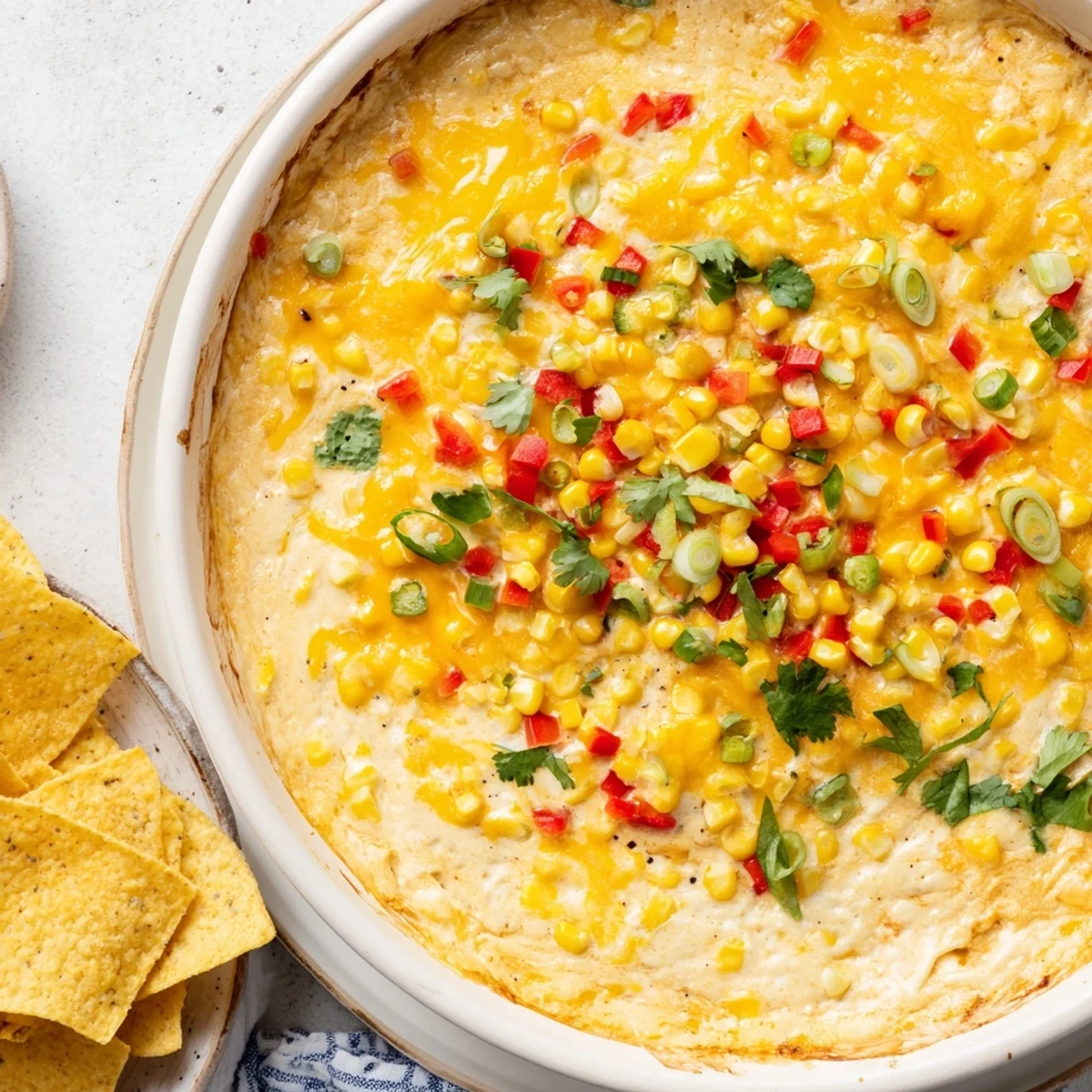 Golden baked corn dip bubbling with melted cheddar and Monterey Jack cheese in a white baking dish
