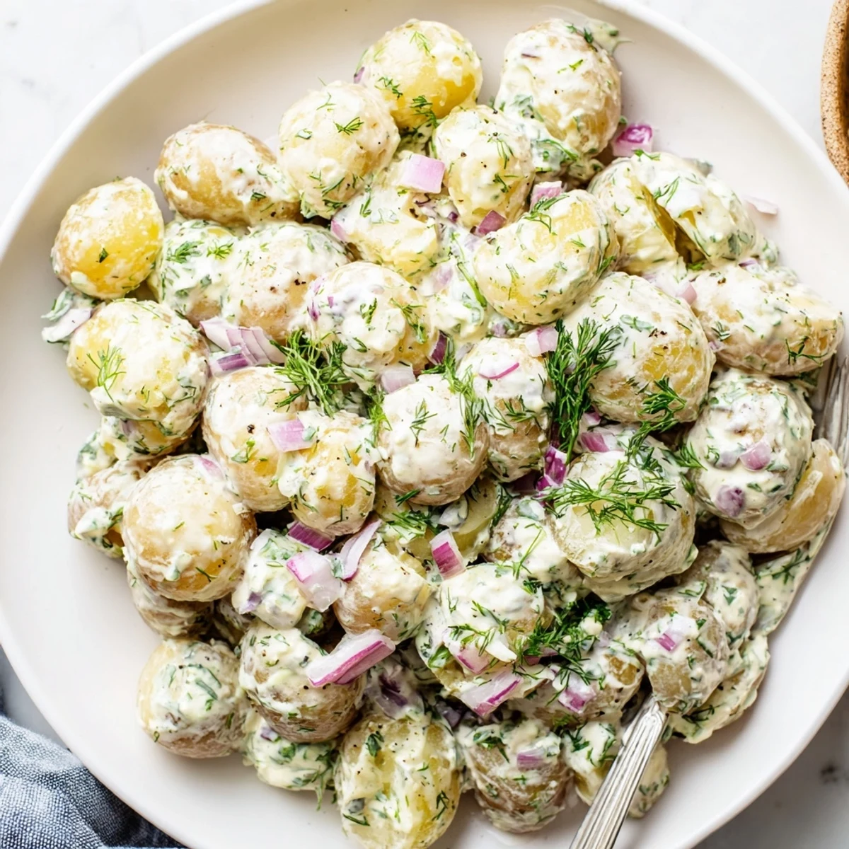 Light and tangy Greek yogurt potato salad featuring colorful vegetables and chopped herbs for summer picnics