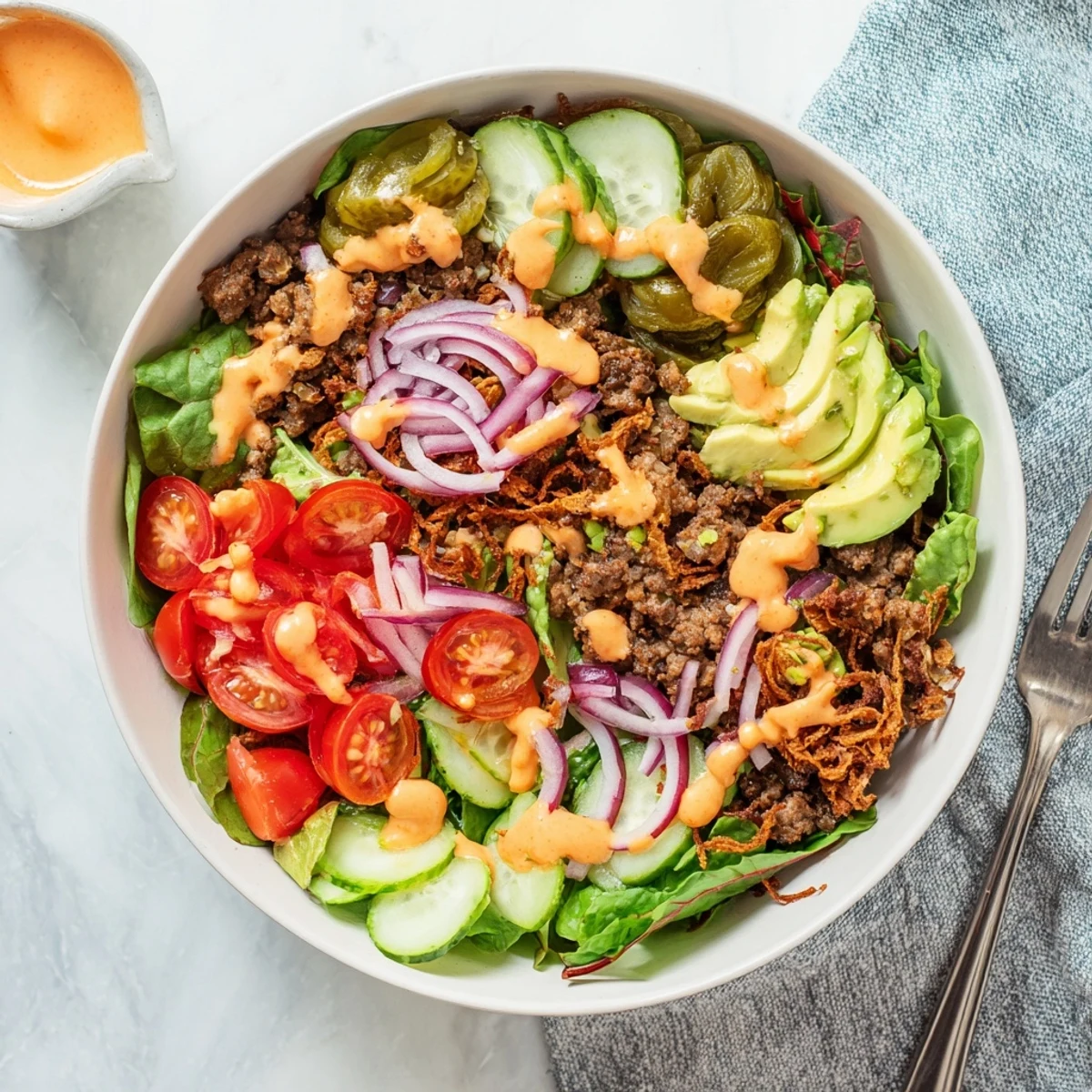 Golden crispy smash burger patties nestled over fresh greens with creamy special sauce drizzled on top