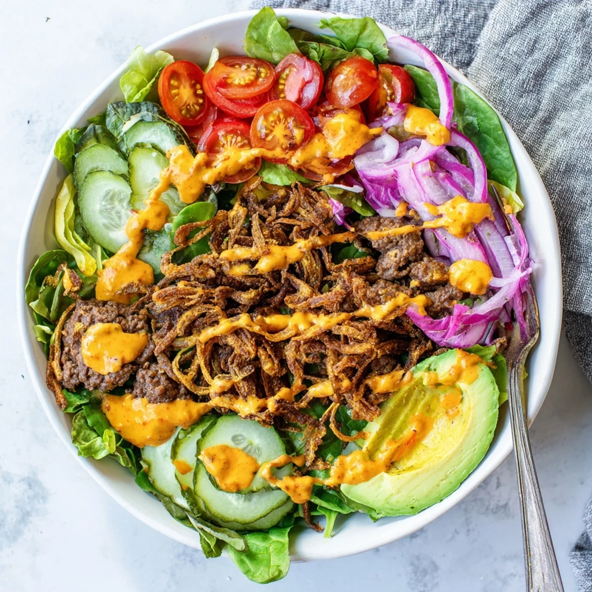 Deconstructed American smash burger bowl with seared ground beef, colorful vegetables, and homemade Thousand Island dressing
