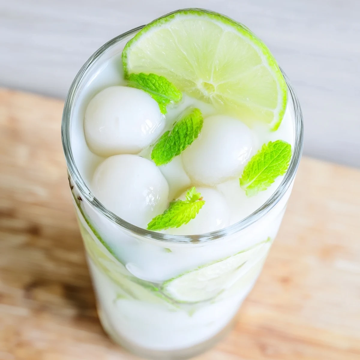 Tropical Coconut Lychee Iced Drink featuring frosty ice cubes and whole lychee fruit floating on top