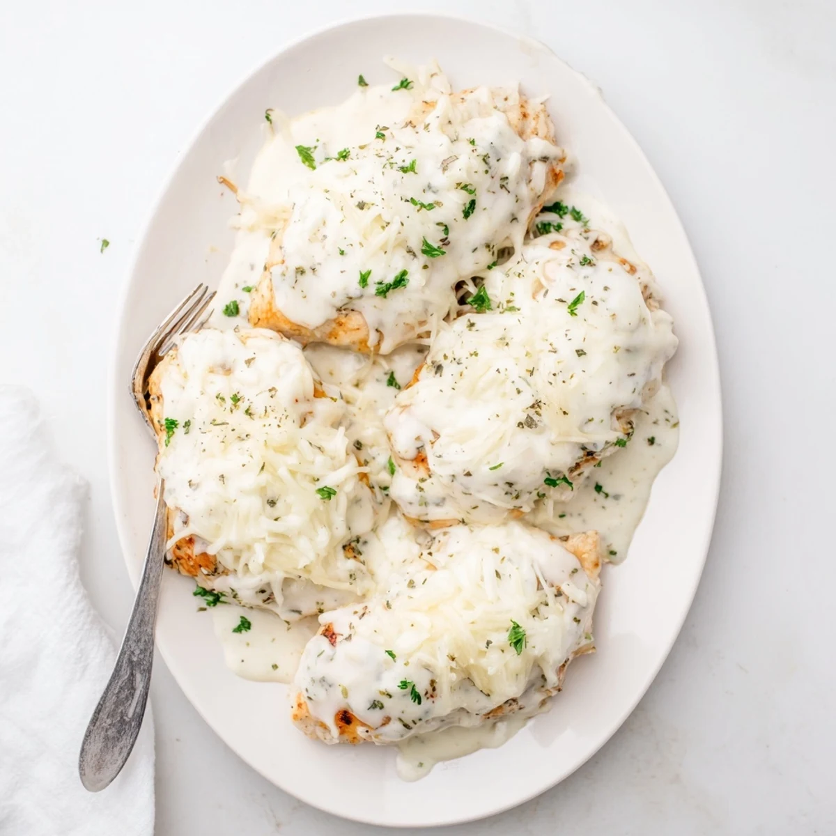 Creamy Parmesan Caesar chicken baking in a dish with golden melted cheese topping