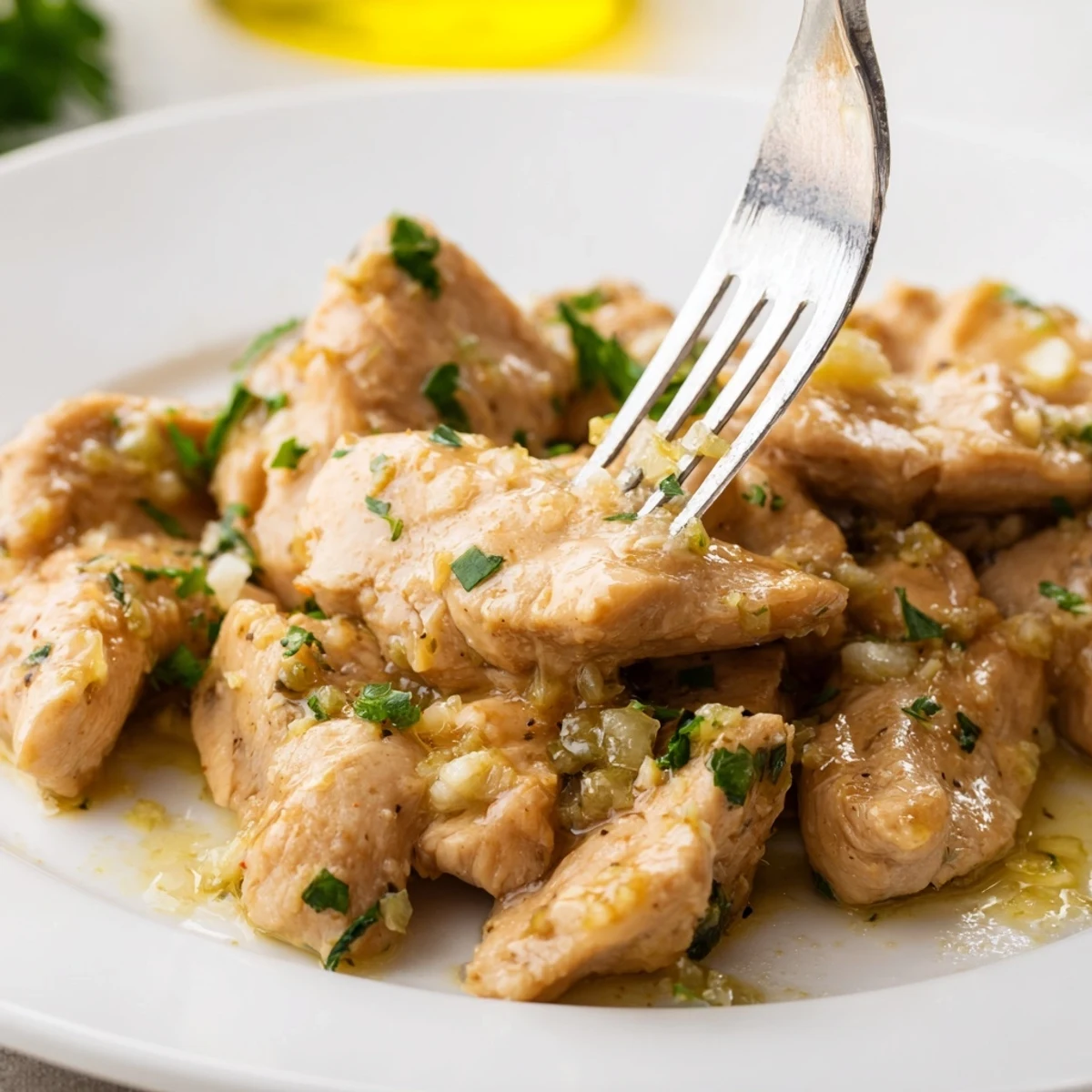Creamy garlic butter chicken crockpot meal served on white plate with green parsley sprinkles
