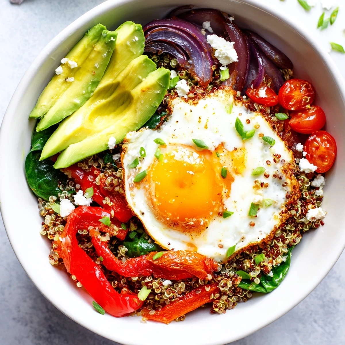 Protein-rich savory quinoa breakfast bowl featuring wilted spinach, cherry tomatoes, and perfectly cooked sunny-side-up egg