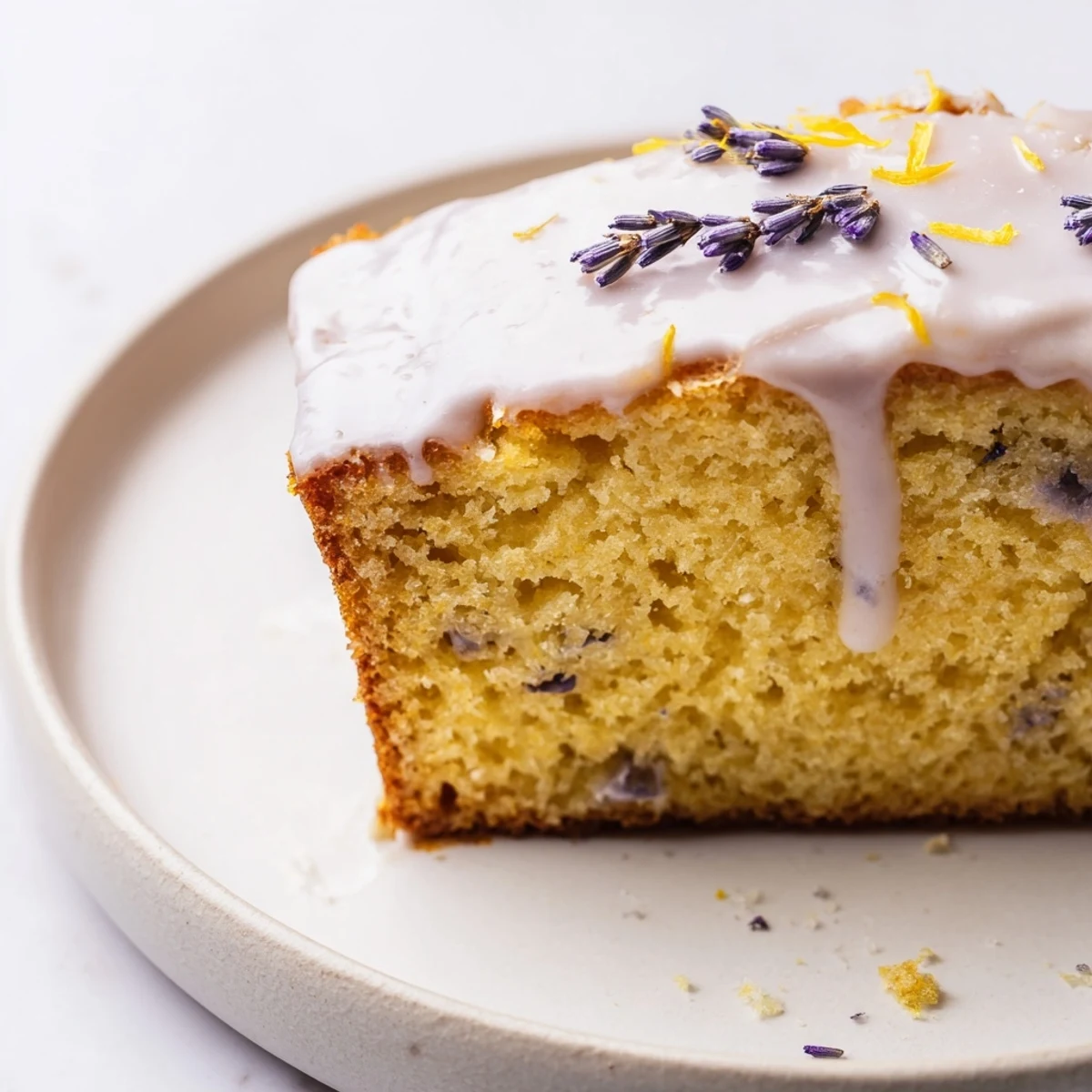 Lavender cake with lemon glaze drizzled over a tender crumb, garnished with fresh purple buds