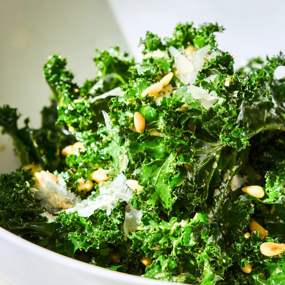 Fresh garlic lemon Parmesan kale salad in a rustic wooden bowl with shaved cheese
