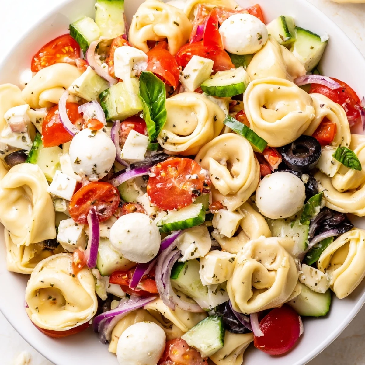 Creamy cheese tortellini salad featuring crisp vegetables and fresh basil in a tangy vinaigrette