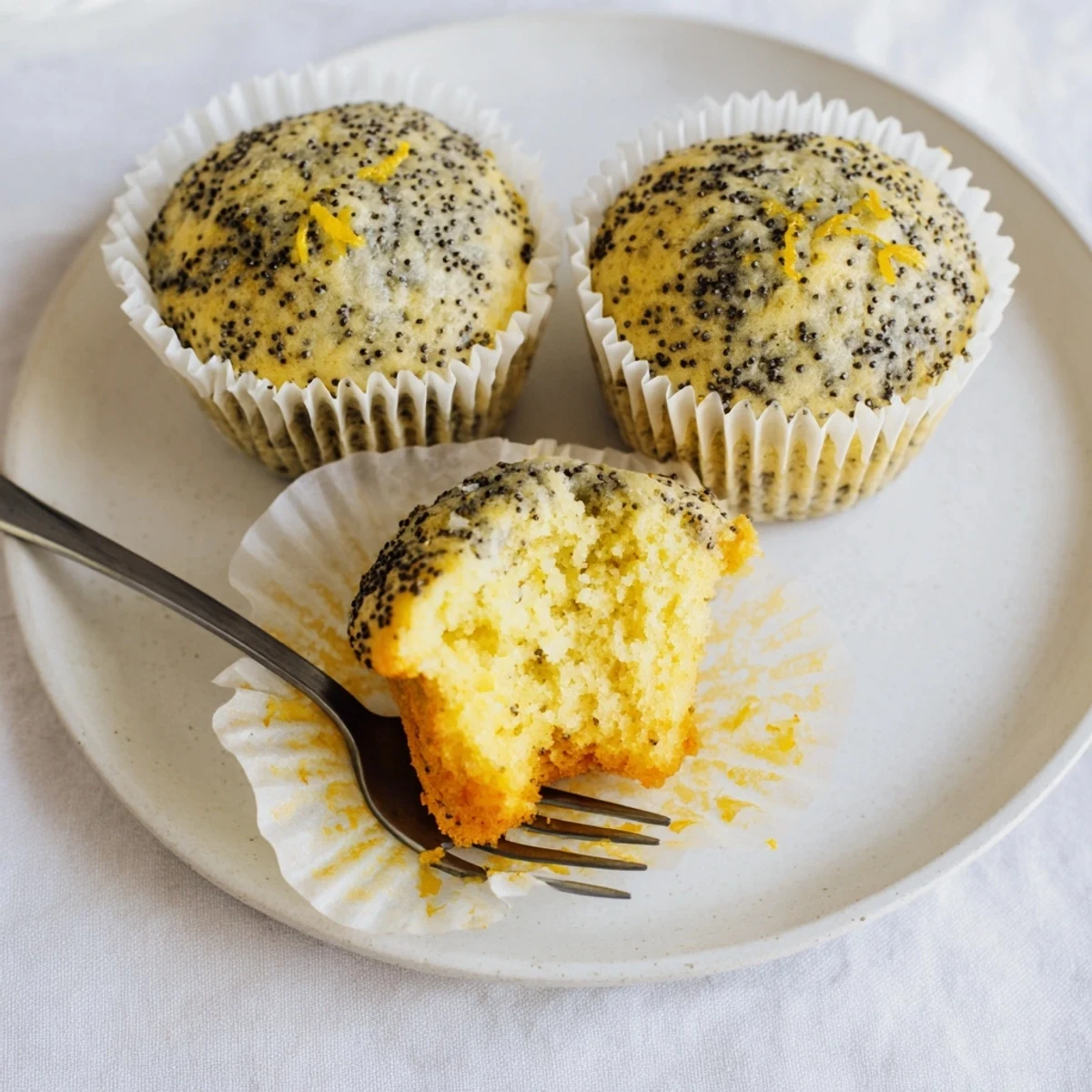 Golden lemon poppy seed muffins with domed tops fresh from the oven on a cooling rack