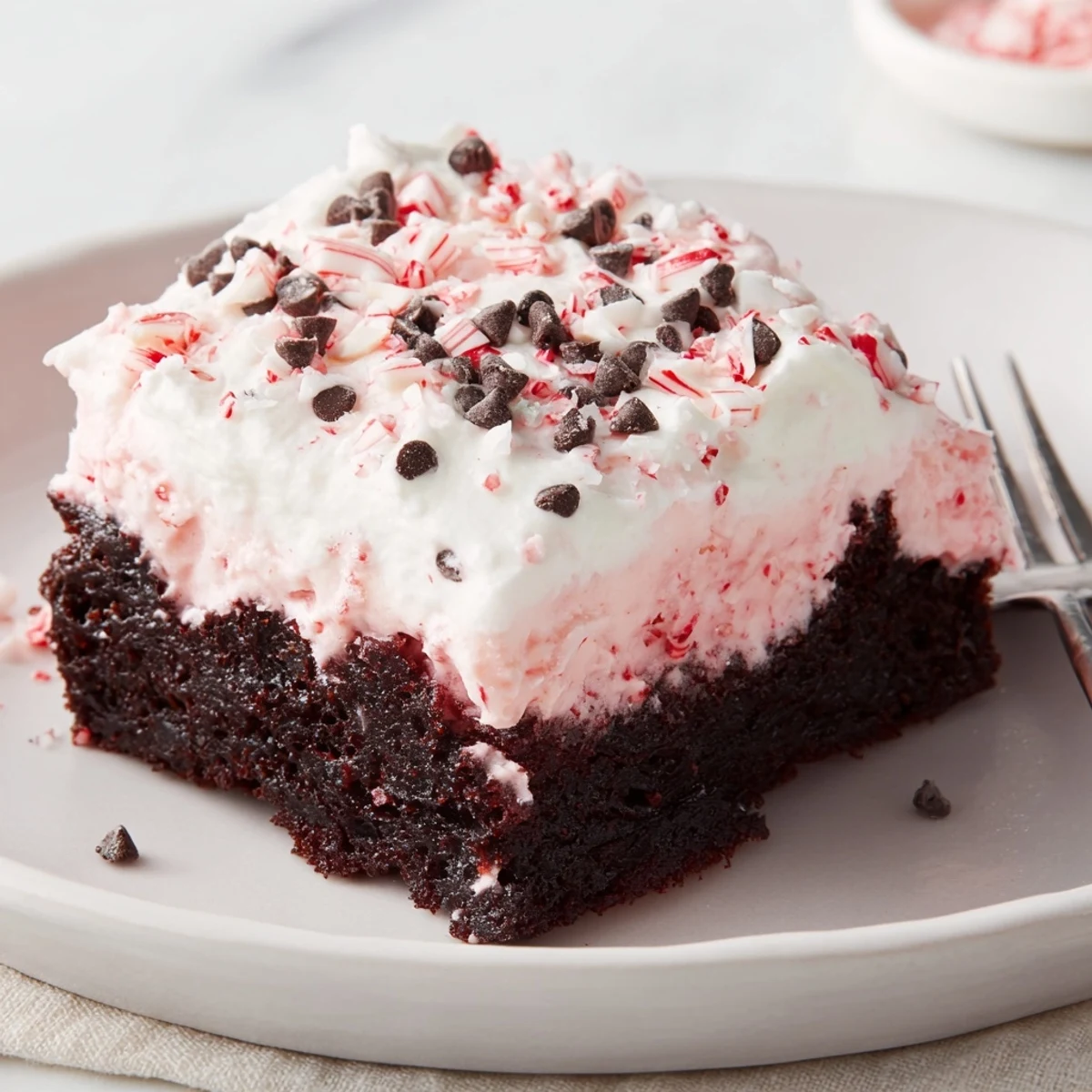 Peppermint Poke Cake chilled with whipped topping, crushed candies glistening