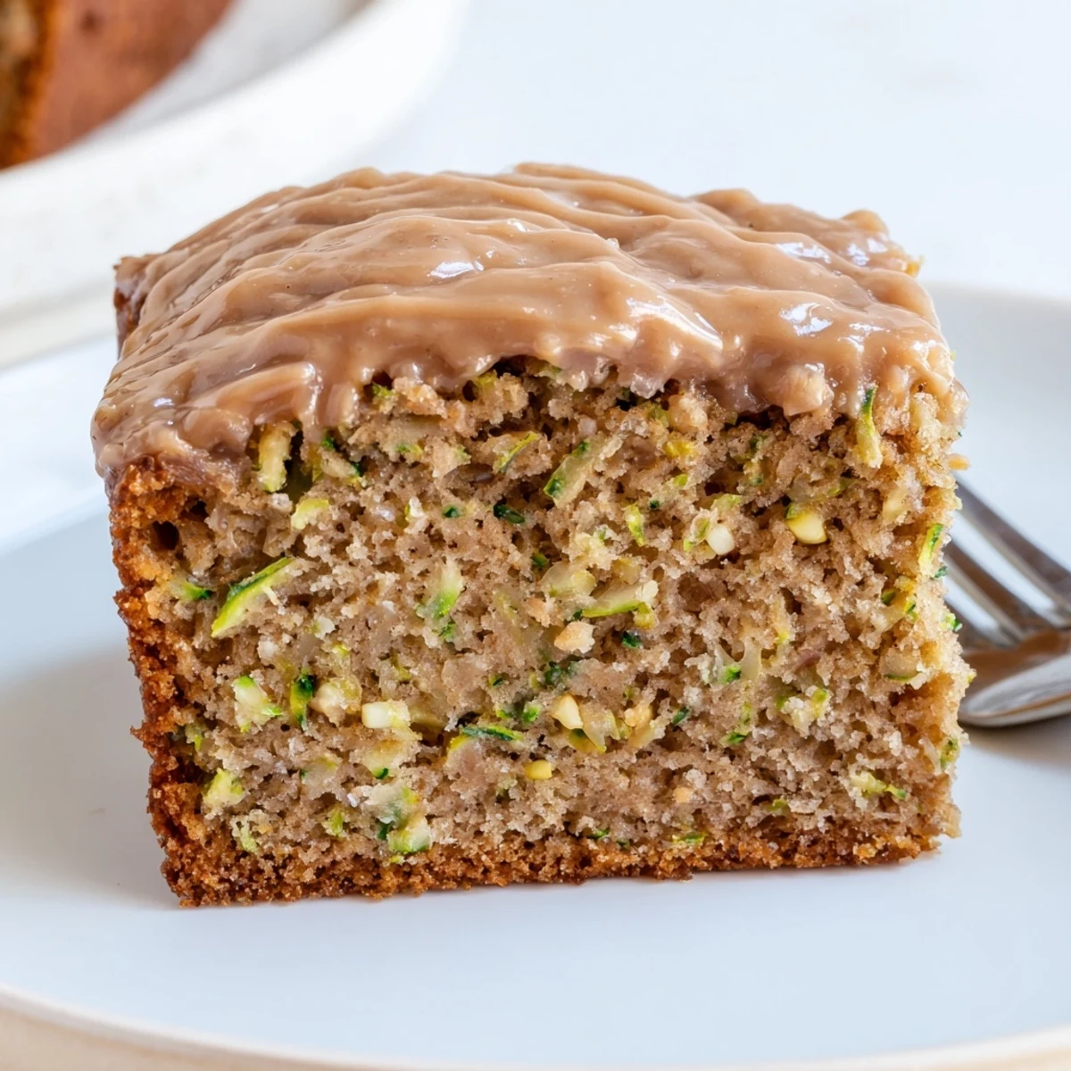 Zucchini Cake With Brown Sugar Icing, moist slice beside steaming cup of coffee