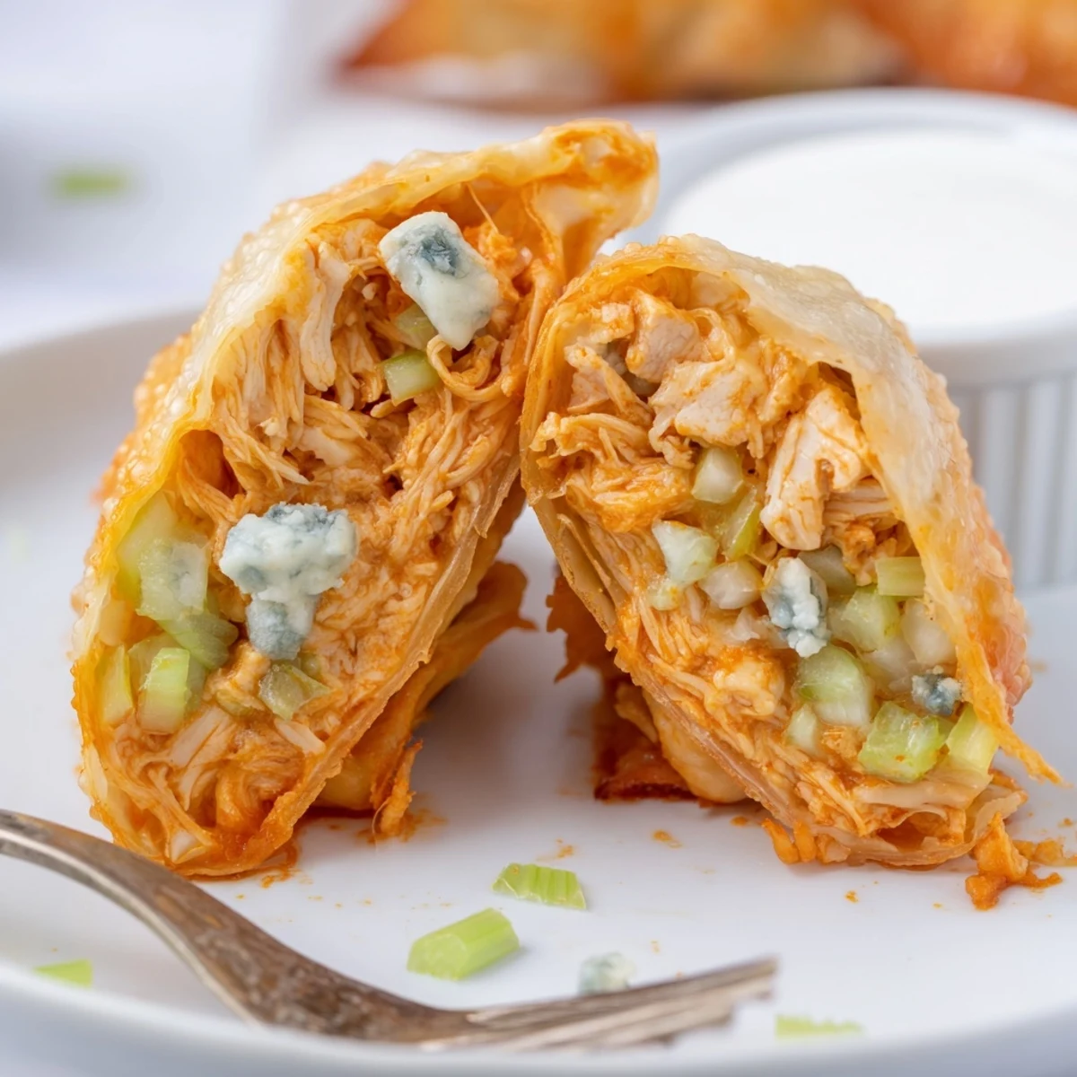 Golden fried Buffalo Chicken Egg Rolls Recipe oozing cheese, celery crunch visible