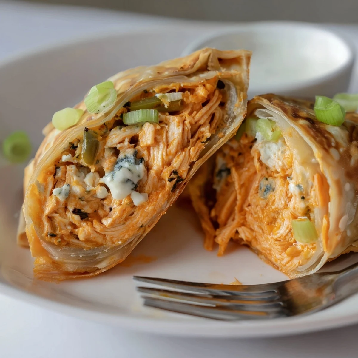 Handheld Buffalo Chicken Egg Rolls Recipe cooling on paper towels, dipping nearby