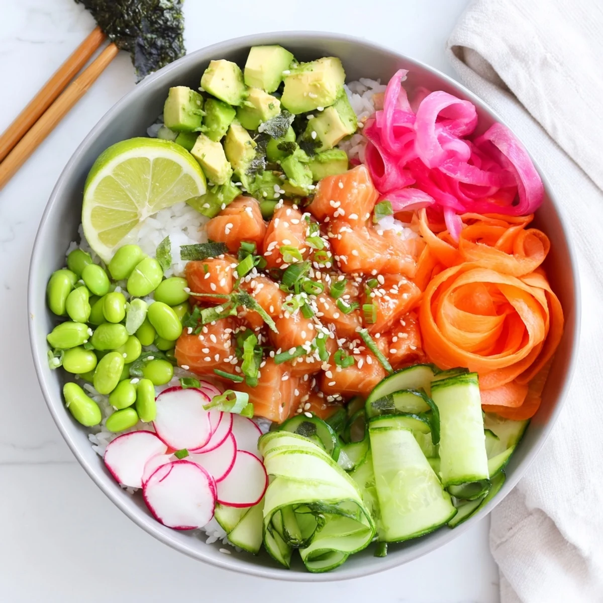 Fresh cubed salmon and avocado poke bowl arranged over rice with crisp vegetable toppings