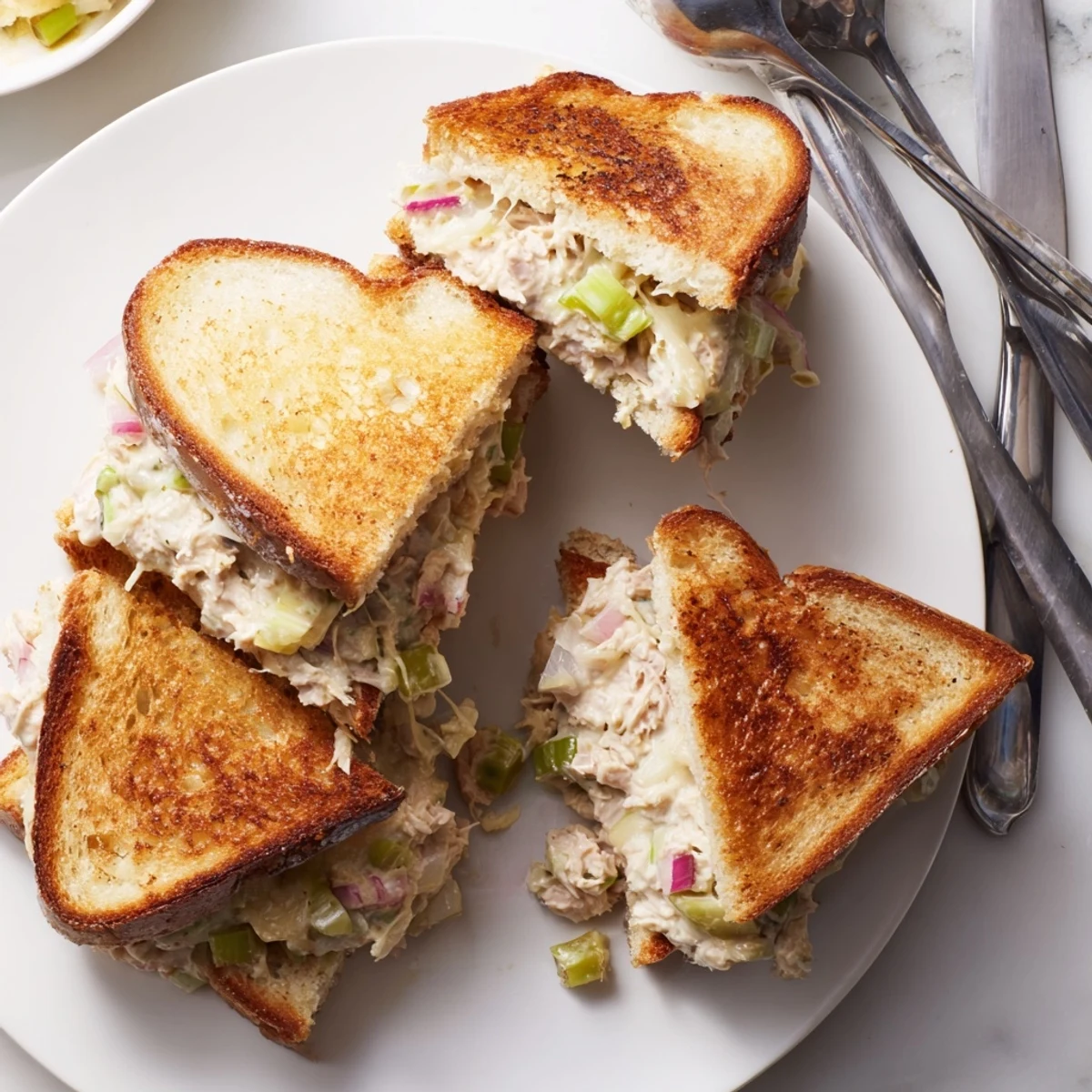 Golden brown tuna melt sandwich featuring melted Swiss cheese and creamy tuna salad on buttered toasted bread