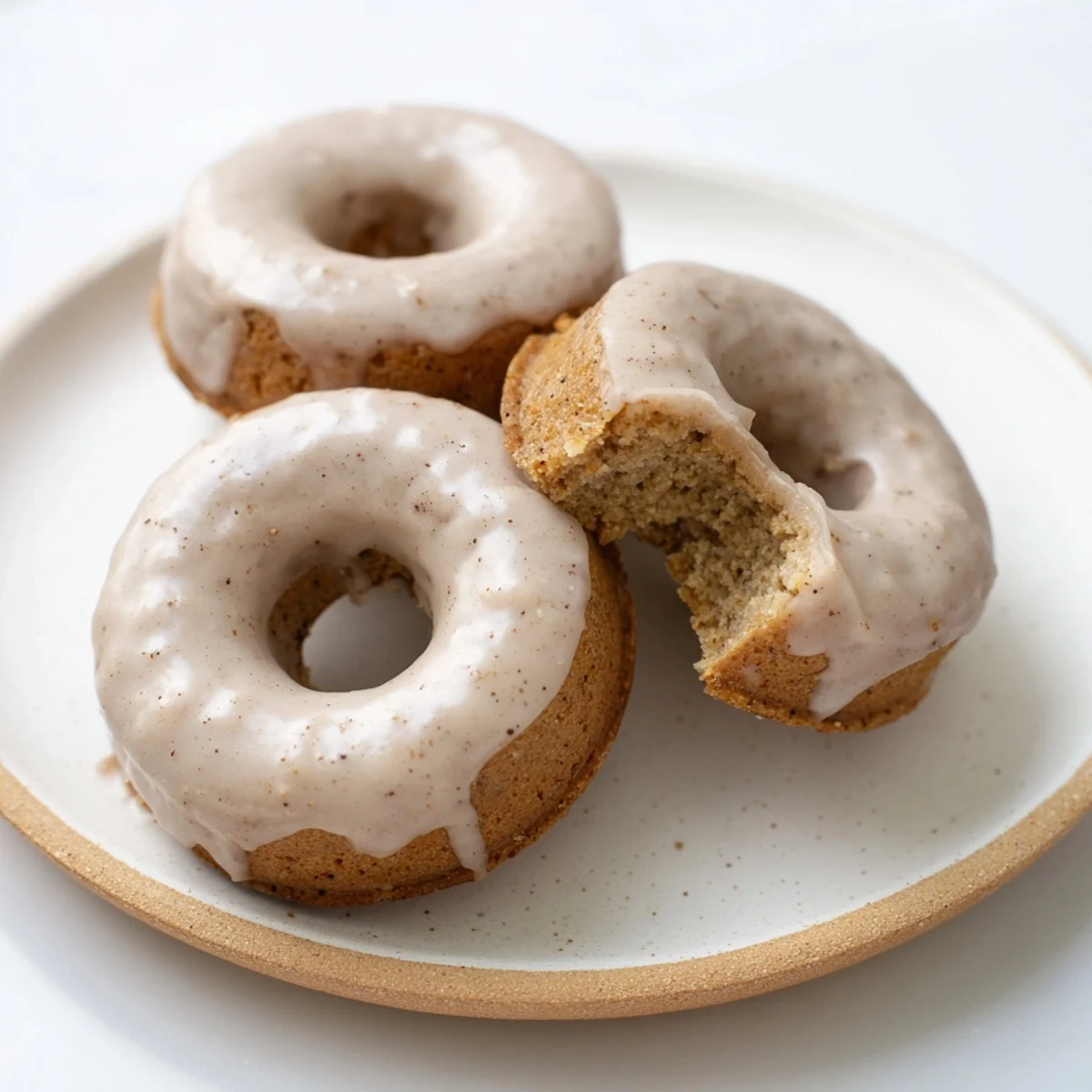 Golden baked banana bread donuts topped with sweet cinnamon glaze on a wire cooling rack