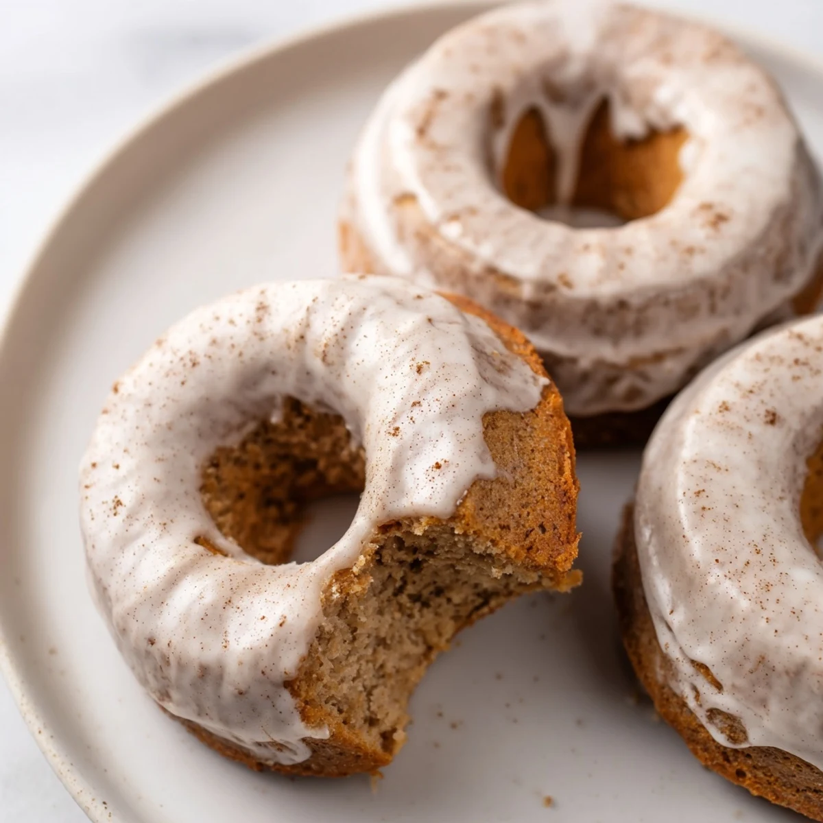 Moist homemade banana bread donuts drizzled with powdered sugar glaze, ready for breakfast
