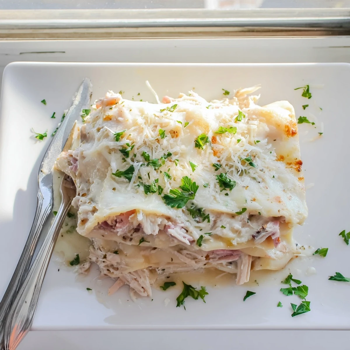 Baked Chicken Cordon Bleu Lasagna squares showing creamy white sauce and melted mozzarella topping